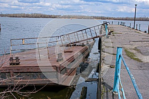 Old rusty sunken pier in the water on the territory of the river port.