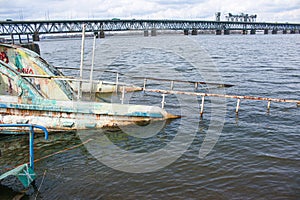 Old rusty sunken ship in the water on the territory of the river port. Old sunken boat on the river