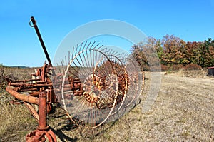 Old rusty tedder standing on a dry field