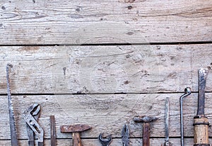 Old, rusty tools lying on a black wooden table. Hammer, chisel, hacksaw, metal wrench. Copy space