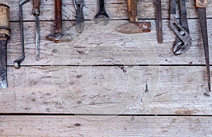 Old, rusty tools lying on a black wooden table. Hammer, chisel, hacksaw, metal wrench.Copy space