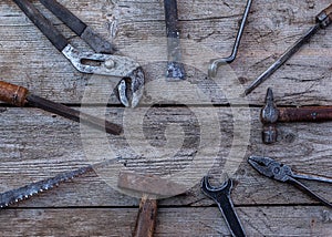 Old, rusty tools lying on a black wooden table. Hammer, chisel, hacksaw, metal wrench.Copy space