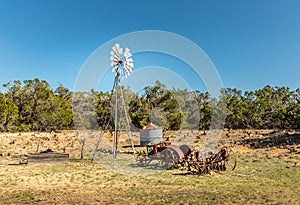 Old rusty tractor and a windmill on the backroads of Texas photo