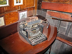 Old rusty typewriter sitting on dusty wooden table in the cabin of an antique wooden boat - very Hemingwayesque