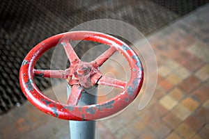 Old rusty valve wheel painted red paint with swellings and peeling selective focus with extension device over out of focus