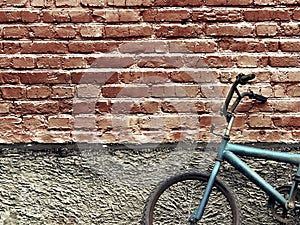 Old rusty vintage bicycle leaning against a brick wall