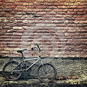Old rusty vintage bicycle leaning against a brick wall