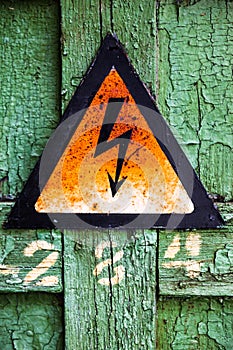 Old rusty warning high voltage sign on cracked wooden surface