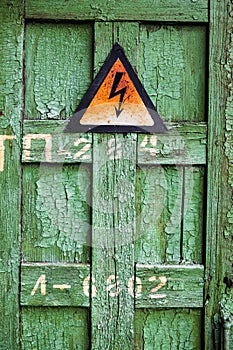 Old rusty warning high voltage sign on cracked wooden surface