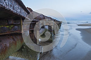 Old rusty wastepipe going into sea.