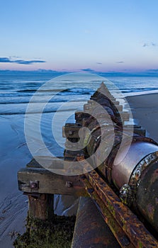 Old rusty wastepipe going into sea.