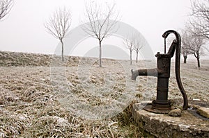 Old rusty water pump on the countryside in winter