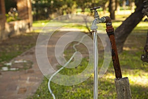 Old rusty water tap with hose in garden