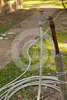 Old rusty water tap with hose in garden