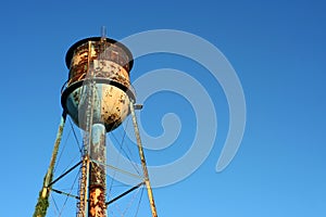 Old rusty watertower against blue sky photo