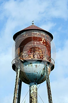 Old rusty watertower against blue sky photo