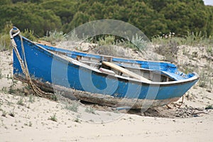 Old rusty and weathered blue boat on the sandy beach