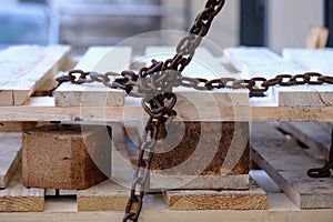 old rusty and weathered iron chain wrapped around wooden pallets