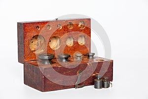 Old rusty weights for scales of different sizes and scales in a wooden box on a white background close-up