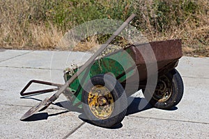 old rusty wheelbarrow garden is filled with dry grass