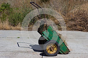 old rusty wheelbarrow garden is filled with dry grass