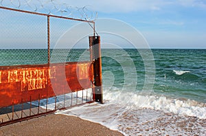 Old rusty wire fence on a seashore. Restricted area on a beach