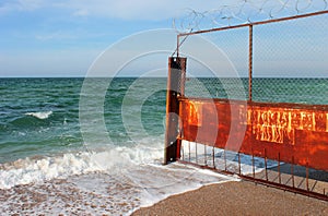 Old rusty wire fence on a seashore. Restricted area on a beach