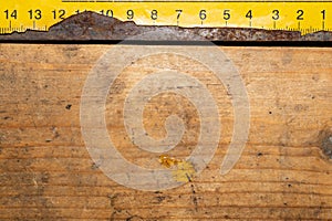 Old rusty yellow ruler with black numbers on a working wooden table. industrial background. carpentry workbench