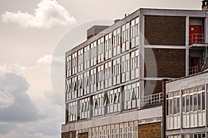 Old 1970`s concrete and brick office building block with sun shining in need of regeneration project to modernise