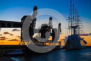 Old sailer five-master sailer in front of three old cranes in evening backlight with great evening skies, Barbados, Carribean Sea