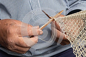 Old sailer mending a fishing net, the tradional way by hand photo
