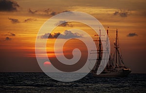 Old sailing ship in the sea at sunset