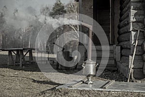 An old samovar heats water outdoors in the village.