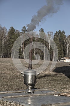 An old samovar heats water outdoors in the village.