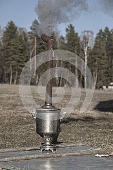 An old samovar heats water outdoors in the village.