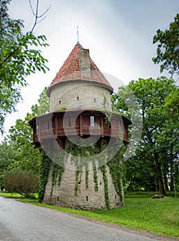 Old Scandinavian Castle Citadel Tower named Kiiu Torn with wooden balcony and red roof behind the green trees. Used for liquor