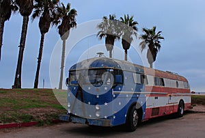 An old school bus with the color of the flag of the United States of America ashore in Santa Monica.