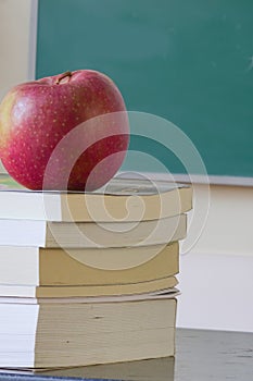 Old school eductation with a chalckboard a books with a red apple on top of the books