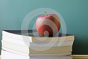 Old school eductation with a chalckboard a books with a red apple on top of the books