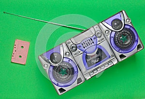 Old school retro tape recorder and audio cassette on a green background.
