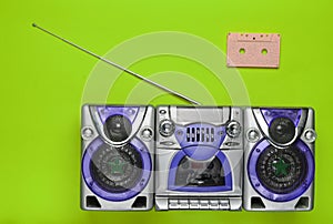 Old school retro tape recorder and audio cassette on a green background. Obsolete technologies. Trend of minimalism. Top view.