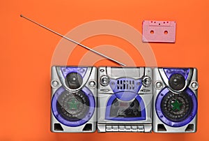 Old school retro tape recorder and audio cassette on an orange background. Obsolete technologies. Trend of minimalism. Top view.