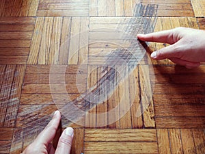 Old, scratched parquet flooring needs maintenance. the parquet is damaged by scratches from prolonged use. Master`s hands show