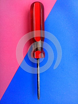 Old screwdriver with red handle and colorful background
