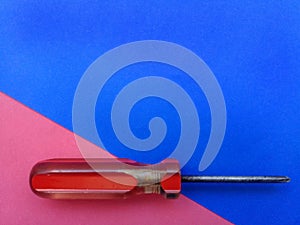 Old screwdriver with red handle and colorful background