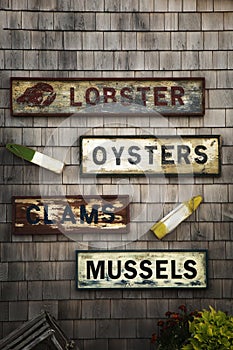 Old seafood name product signs on a wooden shingle wall