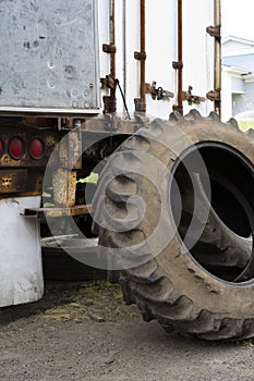 Old semi truck tires without rims stand near an old rusty trailer