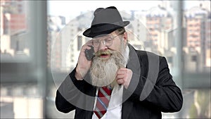 Old senior long-bearded businessman talking on phone.