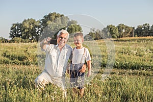 Old senior man and grahdson take selfie with smartphone.  Social network. Weblog. Modern life