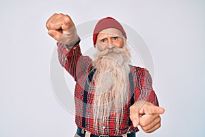 Old senior man with grey hair and long beard wearing hipster look with wool cap pointing to you and the camera with fingers,